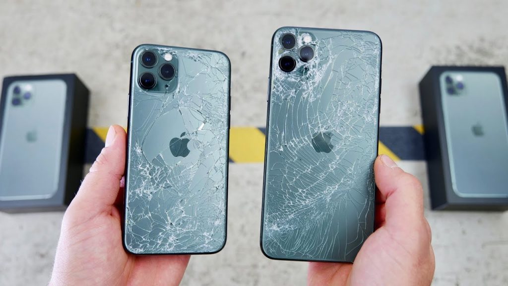 Two hands display two iPhones with cracked screens, highlighting the need for iPhone 11 repair services and associated costs.