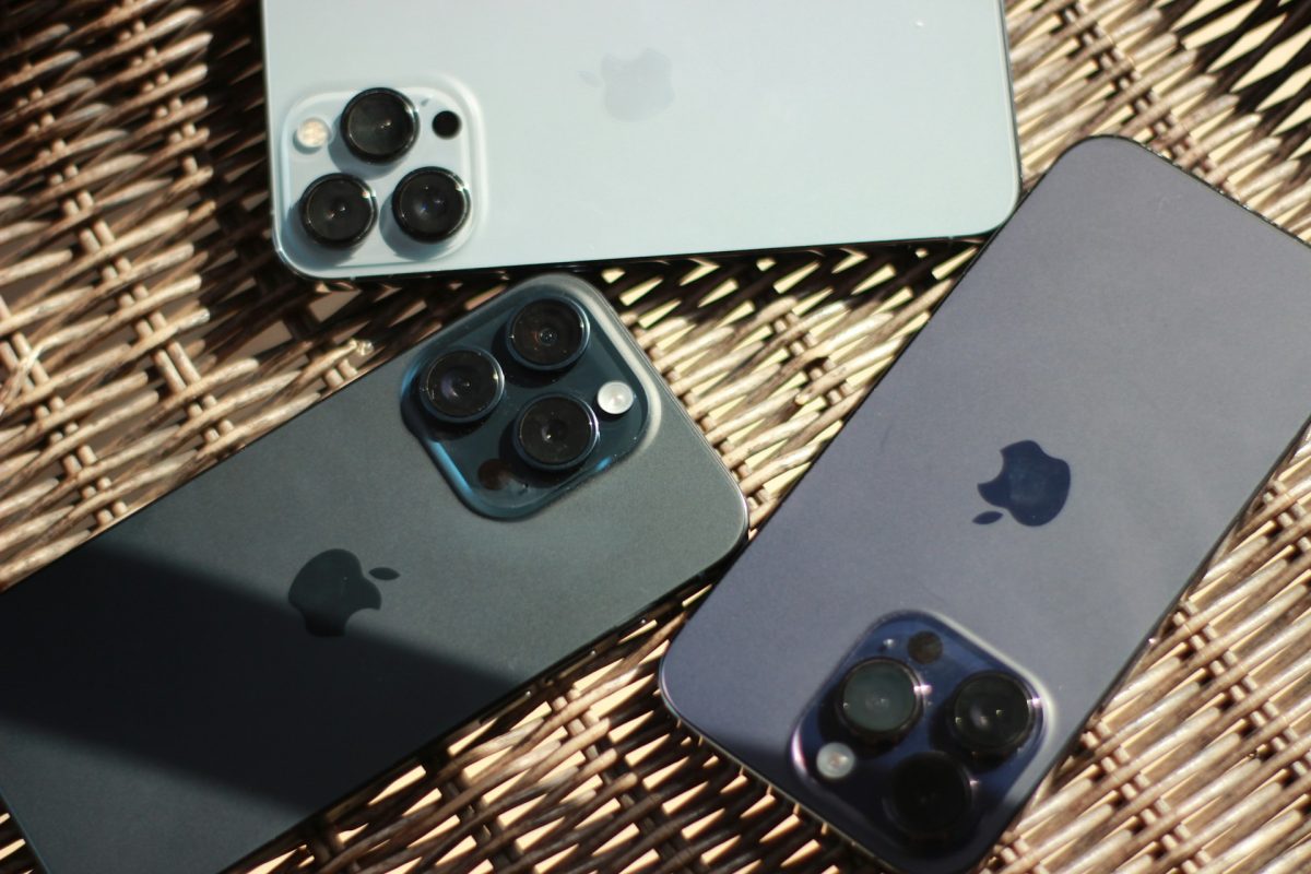 Three iPhones displayed on a wicker table, showcasing their sleek design and functionality.