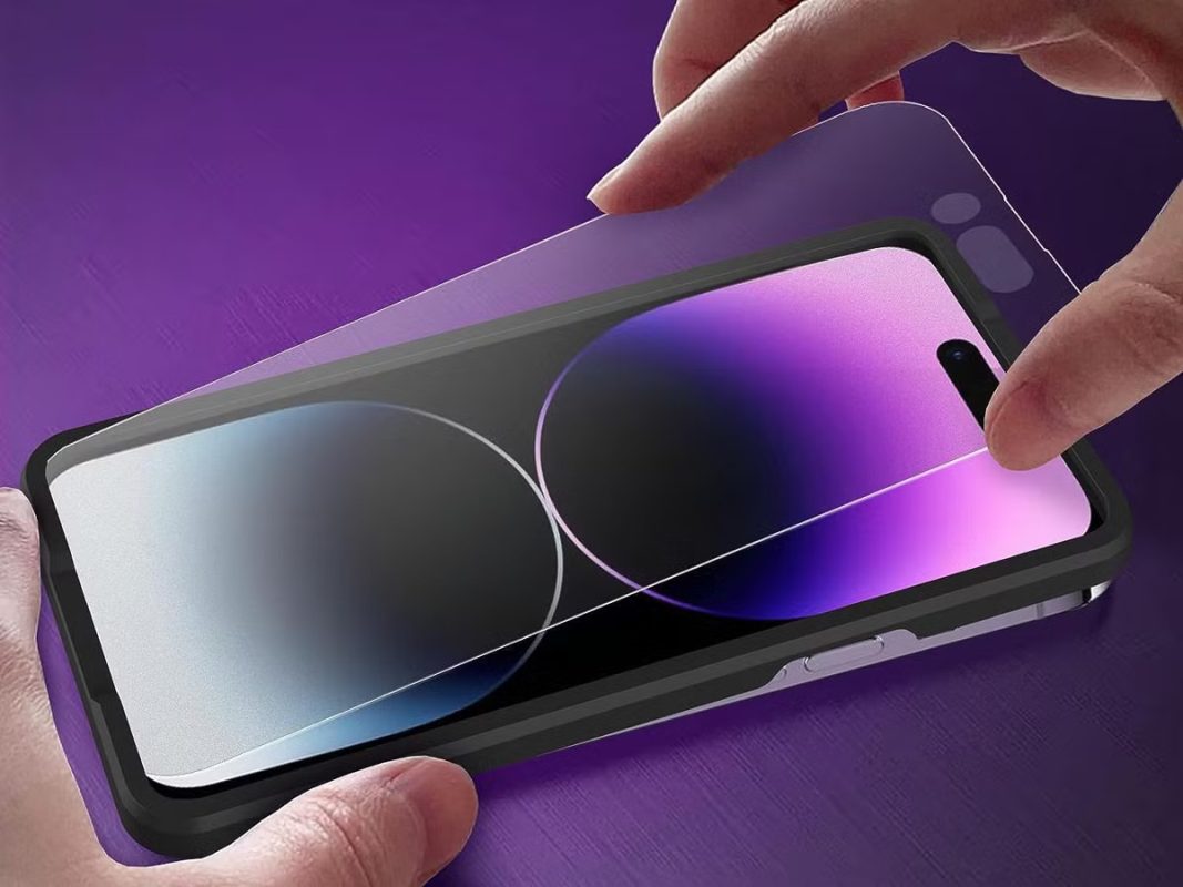 A close-up of a person holding a purple iPhone 11, with a purple background that enhances the phone's vivid hue.