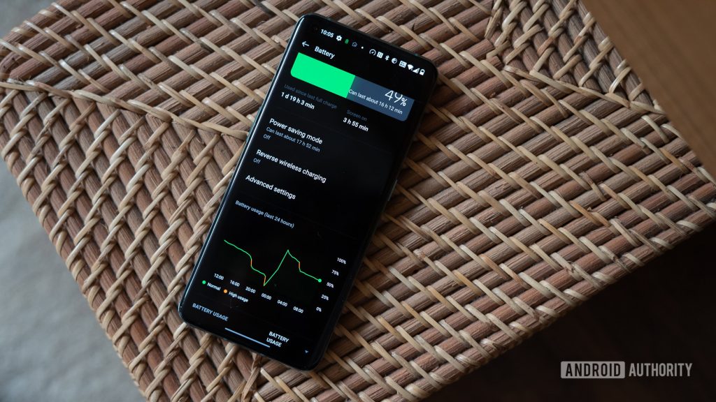 A smartphone displaying battery usage statistics on a woven surface, showing 49% battery remaining with usage graphs.