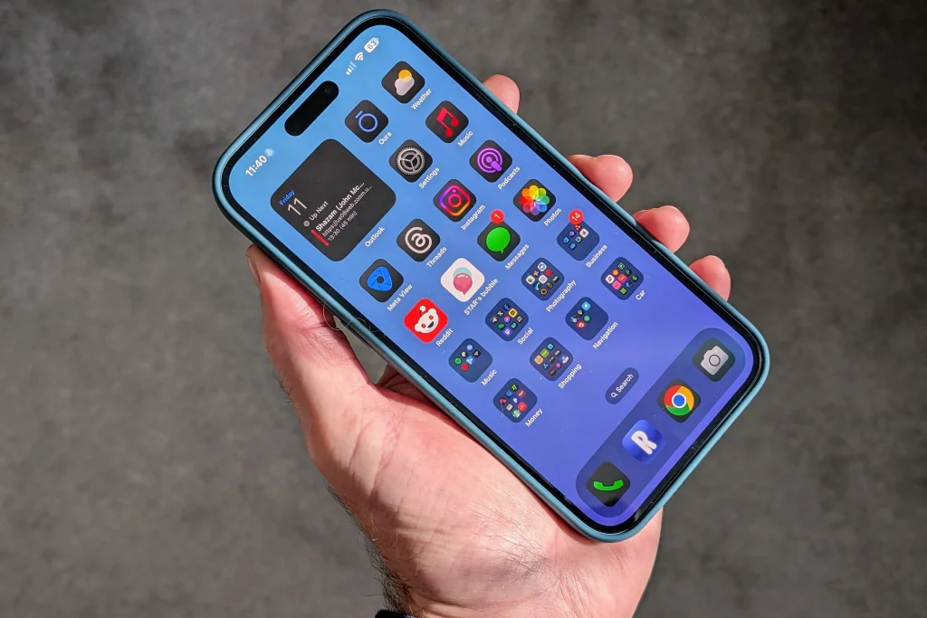 A hand holds a smartphone displaying a vibrant home screen filled with colorful app icons and a calendar widget showing the date.