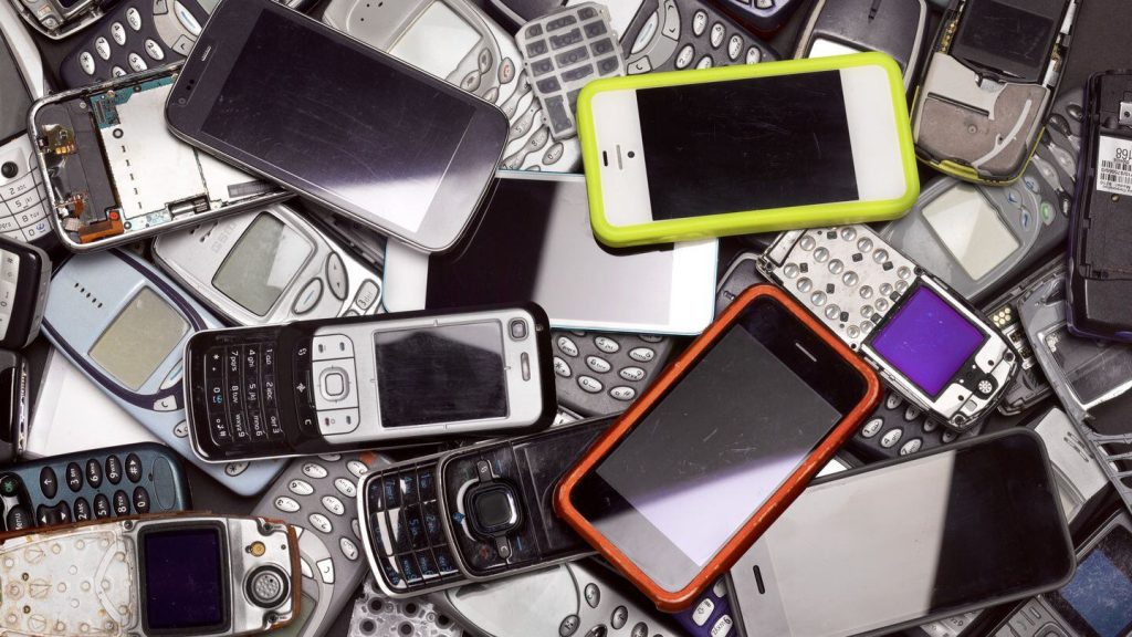 A pile of assorted mobile phones, including smartphones and older models, some disassembled, showcasing various designs and colors.