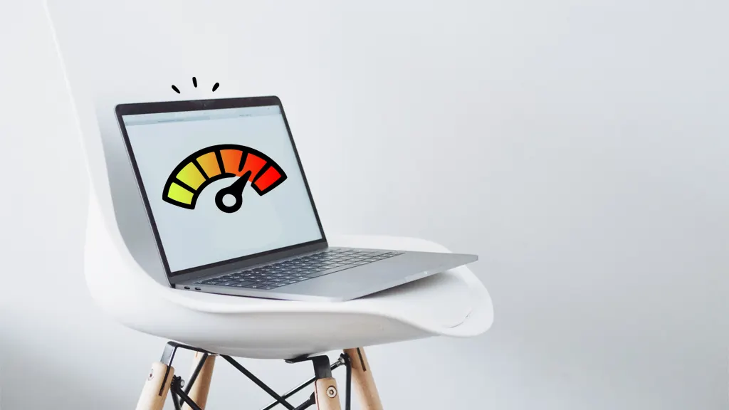 A laptop on a white chair displays a colorful speedometer graphic indicating performance levels.