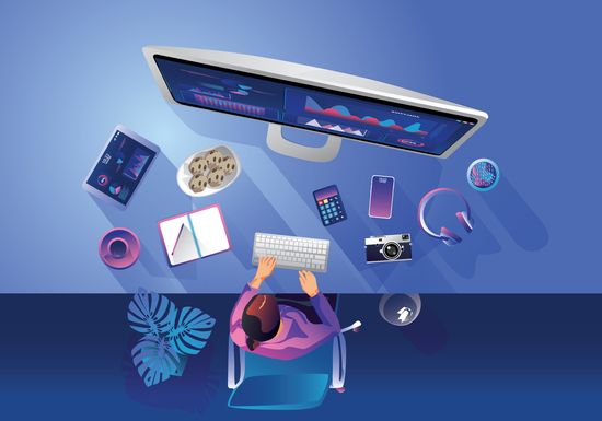 A top-down view of a person at a desk with a computer, data charts, phone, notebook, snacks, and plant, showcasing a creative workspace.